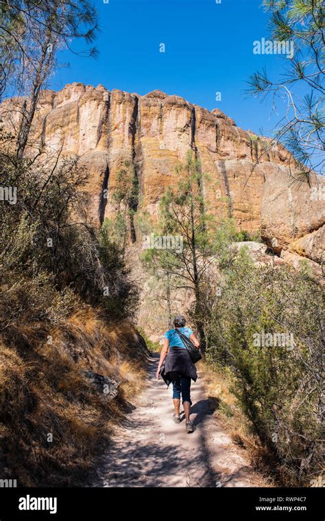 A Woman Walking Up The Balconies Cave Trail Below Massive Cliffs In The