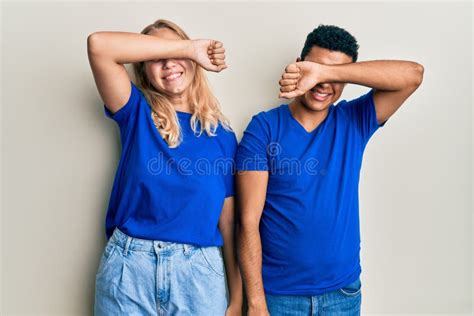 Young Interracial Couple Wearing Casual Clothes Covering Eyes With Arm