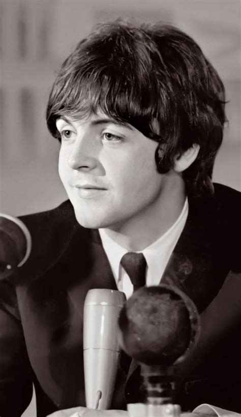 A Man In A Suit And Tie Sitting At A Table With An Old Microphone