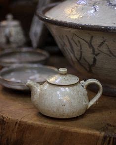 A White Tea Pot Sitting On Top Of A Wooden Table Next To Other Plates