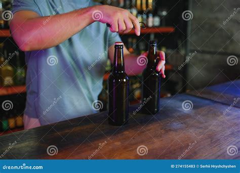 Barman Bottle Of Beer Nearby Empty Glass On Wooden Bar Counter In