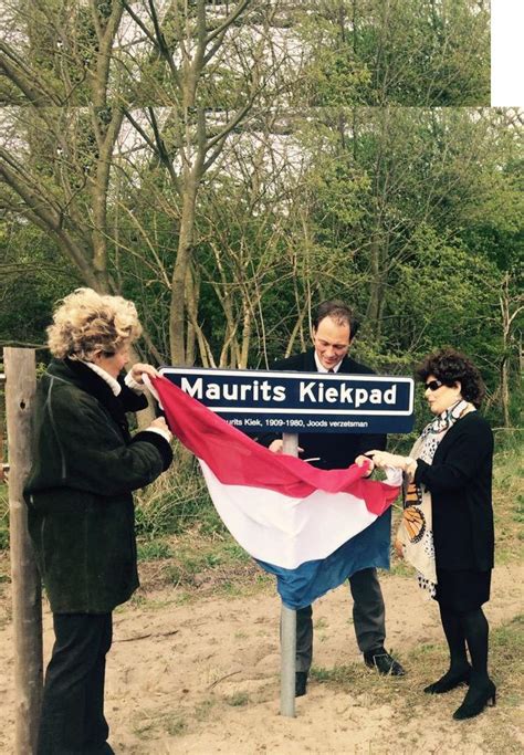 Three People Standing Around A Sign With A Flag Hanging From It S Pole