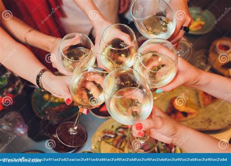 Human Hands With Glasses Of Red Wine Clinking Them Over Served Table