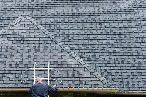 Man On A Ladder Installing Exterior Christmas Lights Del Colaborador