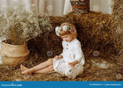 Une Jolie Petite Fille Est Assise Dans Le Hayloft Avec Un Lapin Image