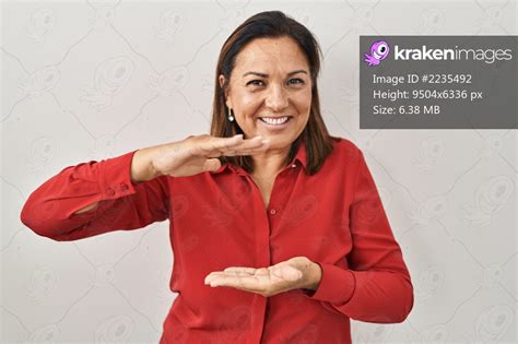 Hispanic Mature Woman Standing Over White Background Gesturing With Hands Showing Big And Large