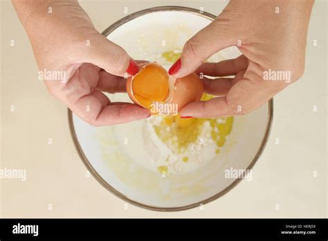 Woman Cracking An Egg Into Bowl Of Flour Stock Photo Alamy