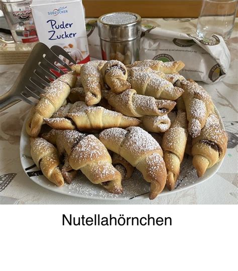 A Plate Full Of Pastries With Powdered Sugar On Them And A Fork In The