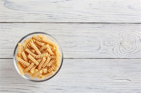 Premium Photo Uncooked Fusilli Pasta In Glass Bowl On White Wooden