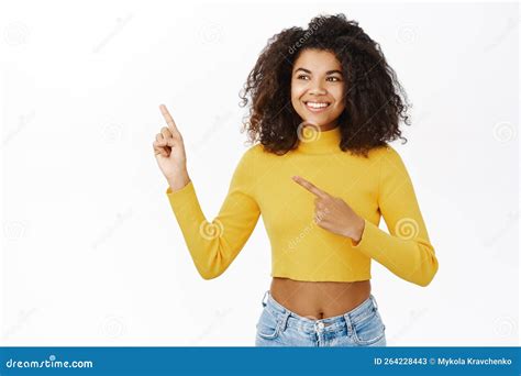 Portrait Of Enthusiastic African American Woman With Curly Hair Pointing Fingers Left Showing