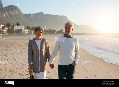 Portrait Of A Happy Senior Couple Taking A Walk On The Beach Together Mature Couple Holding