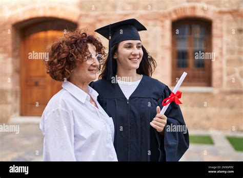 Two Women Mother And Daughter Holding Graduate Diploma At Campus