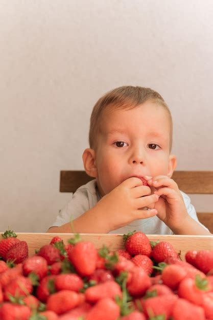 Niño Lindo Comiendo Fresa En Una Caja De Madera De Fondo Gris Llena De