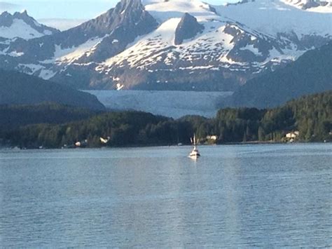 A Boat Floating On Top Of A Lake Surrounded By Snow Covered Mountain