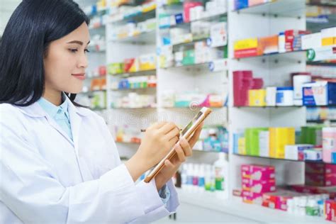 Pharmacist Working With A Tablet Computer In The Pharmacy Holding It In