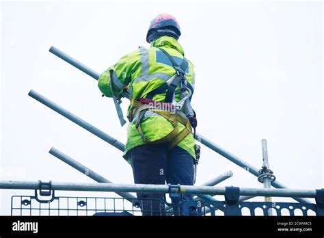 Scaffold Worker Dismantling Access Structure On Construction Building