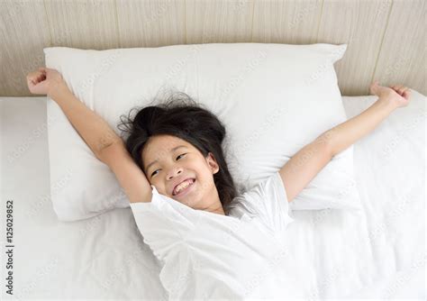 Portrait Of Happy Young Asian Girl Lying In Bed After Waking Up And