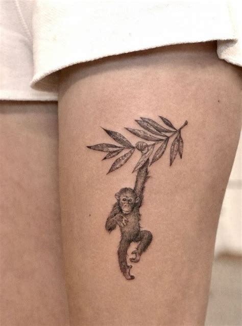 A Woman S Thigh With A Tattoo Of A Monkey Hanging From A Tree Branch