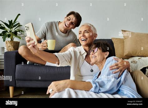 Lesbian Parents And Their Adult Son Share Laughter And Smiles While Taking A Cozy Selfie At Home