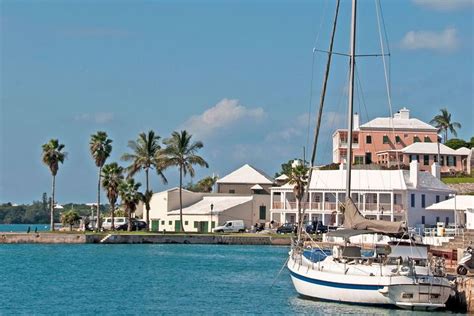 A Sailboat Is Docked In The Water Next To Some Houses And Palm Trees On