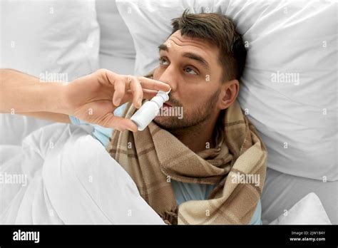 Sick Man With Nasal Spray Lying In Bed At Home Stock Photo Alamy