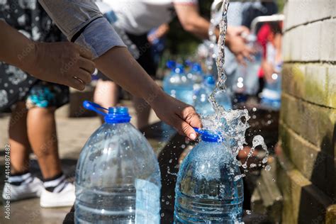 People Collecting Natural Spring Water With Litre Plastic Water