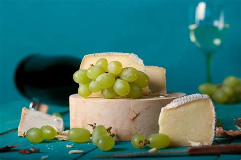 Lonchas De Queso Uvas Blancas Cuchillo Vaso Y Una Botella De Vino