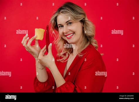 Smiling Pleased Blonde Woman Showing Junk Chili Pepper And Yummy Salty Potato Chips And Look At
