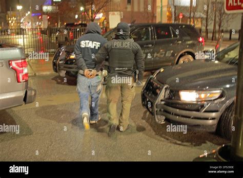 A Detroit Police Officer Leads An Arrested Man Away In Handcuffs