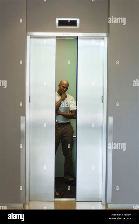 Young Man Standing In Elevator With Hand Under Chin Doors Closing