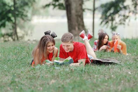 Pares De Los Estudiantes Que Mienten En La Hierba En El Parque Y Que