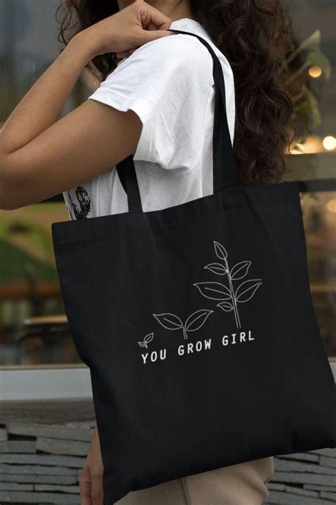 A Woman Carrying A Black Tote Bag That Says You Grow Girl