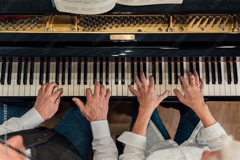 Overhead view of four hands from older couple playing a grand piano Stock Photo | Adobe Stock