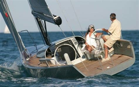 Two People Sitting On The Front Of A Sailboat In The Ocean With Sails Down