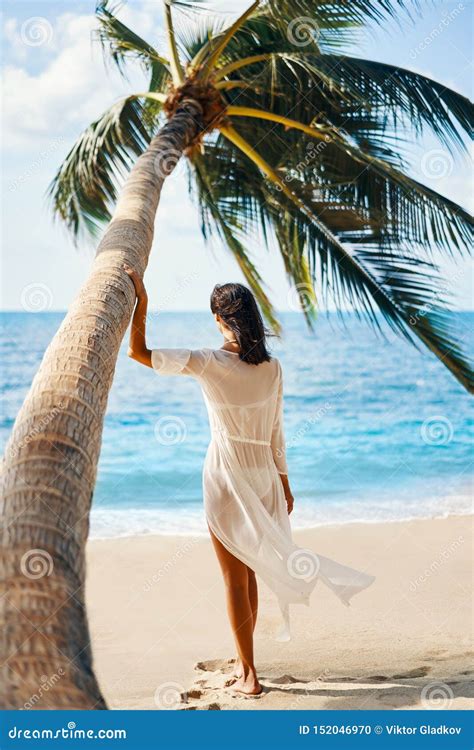 Back View Of Pretty Young Woman Relax And Enjoy Sea Standing Under Palm