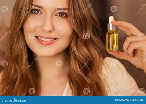 Beautiful Woman Holding Organic Oil Serum Bottle And Smiling Evening