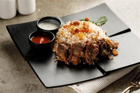 Premium Photo | Mutton biryani with raita and sauce served in a dish ...