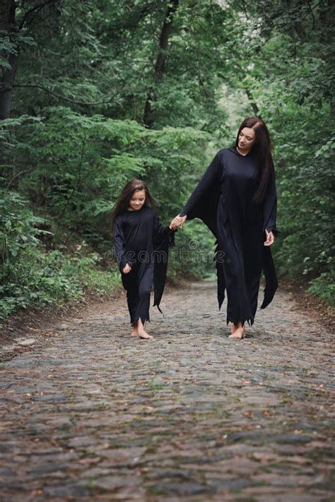 Madre E Hija Vestidas De Negro Caminan Por El Bosque Oscuro Foto De