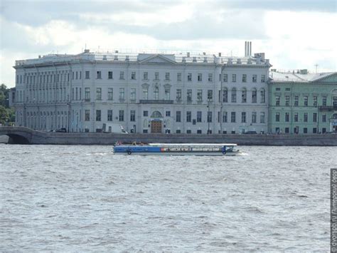 A Large Building Sitting On The Side Of A River Next To A Boat In Front