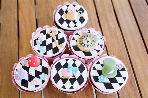 cupcakes decorated with black and white designs on wooden table next to ...