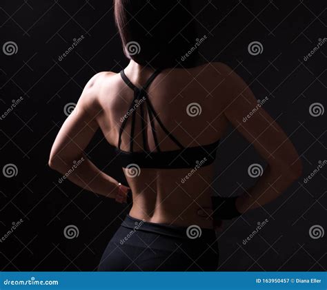 Back View Of Girl With Muscular Body Posing Over Black Stock Image