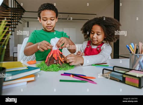 Sister and brother having fun making DIY volcano model from kids play ...