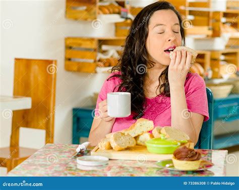 Pretty Brunette Woman Sitting At Table Inside Bakery Holding Cup Of