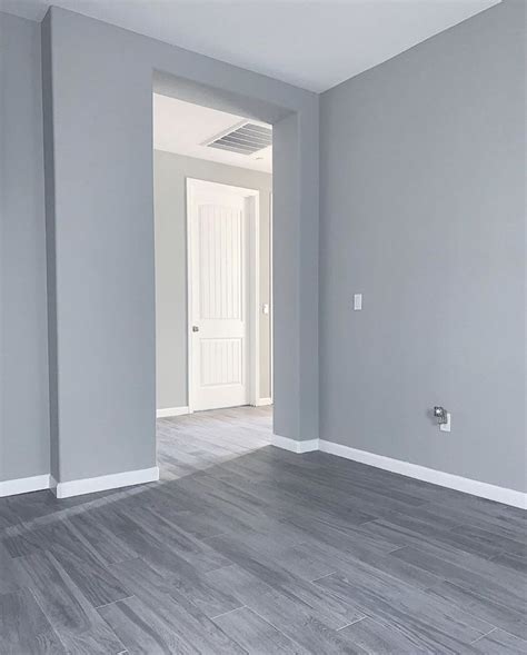 An Empty Room With Gray Walls And Wood Flooring In The Foreground Is A