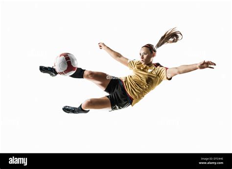 Studio Shot Of Young Female Soccer Player Kicking Ball Mid Air Stock