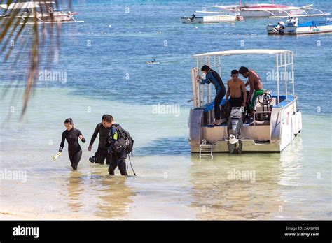 Panglao, Bohol, Philippines - January, 27, 2020: Scuba divers get off the boat to the beach ...