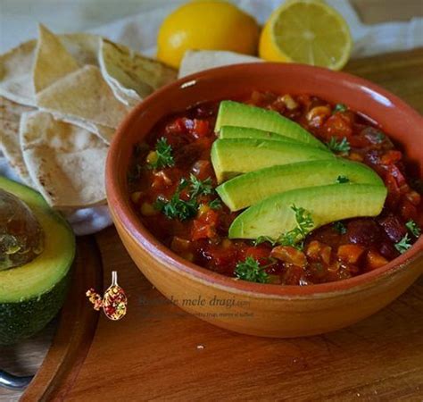 A Bowl Of Chili With Avocado And Tortilla Chips On The Side