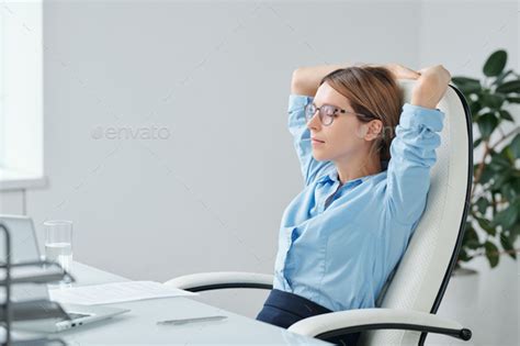 Young Restful Businesswoman Keeping Hands Behind Head While Relaxing In