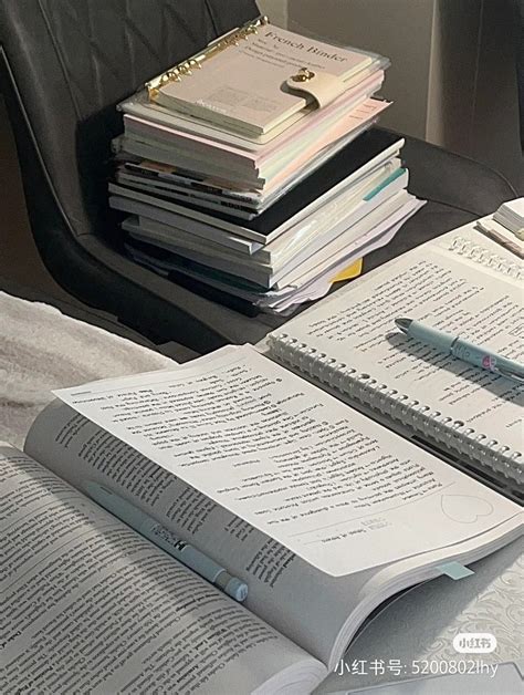 An Open Book Sitting On Top Of A Bed Next To A Pile Of Notebooks