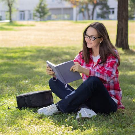 Premium Photo Woman Sitting On The Grass And Reading Book